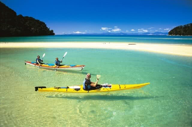 Image of people kayaking in the Abel Tasman National Park with crystal clear waters and golden sandy beaches