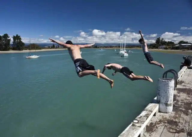 Image of lads jumping off the pier in Mapua on a sunny day