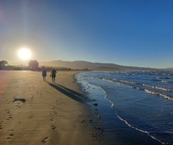 Two people walking along the beach at sunset