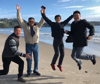 Four people jumping and smiling on a beach