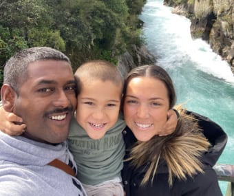 Family of three taking a selfie by a waterfall with smiling faces