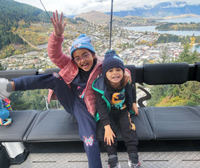 Two kids on a gondola with mountains in the background