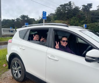 People in a white GO Rentals SUV making peace signs through the windows