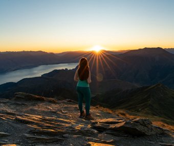 Woman standing on a mountain peak at sunrise