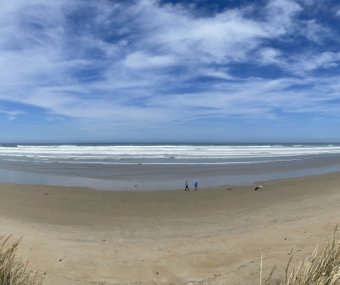 Wide sandy beach with ocean waves and a bright blue sky