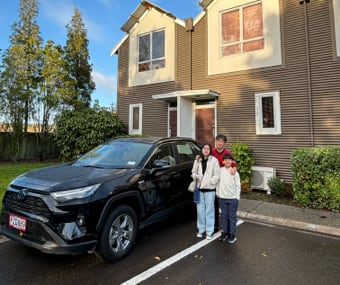 Family standing in front of a black GO Rentals SUV, parked outside a house