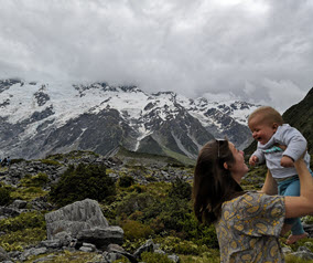 Woman holding a baby with snowy mountains in the background