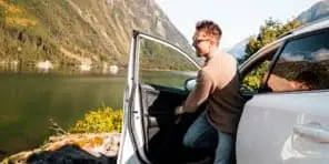 Image of a man stepping out of a vehicle parked beside a lake